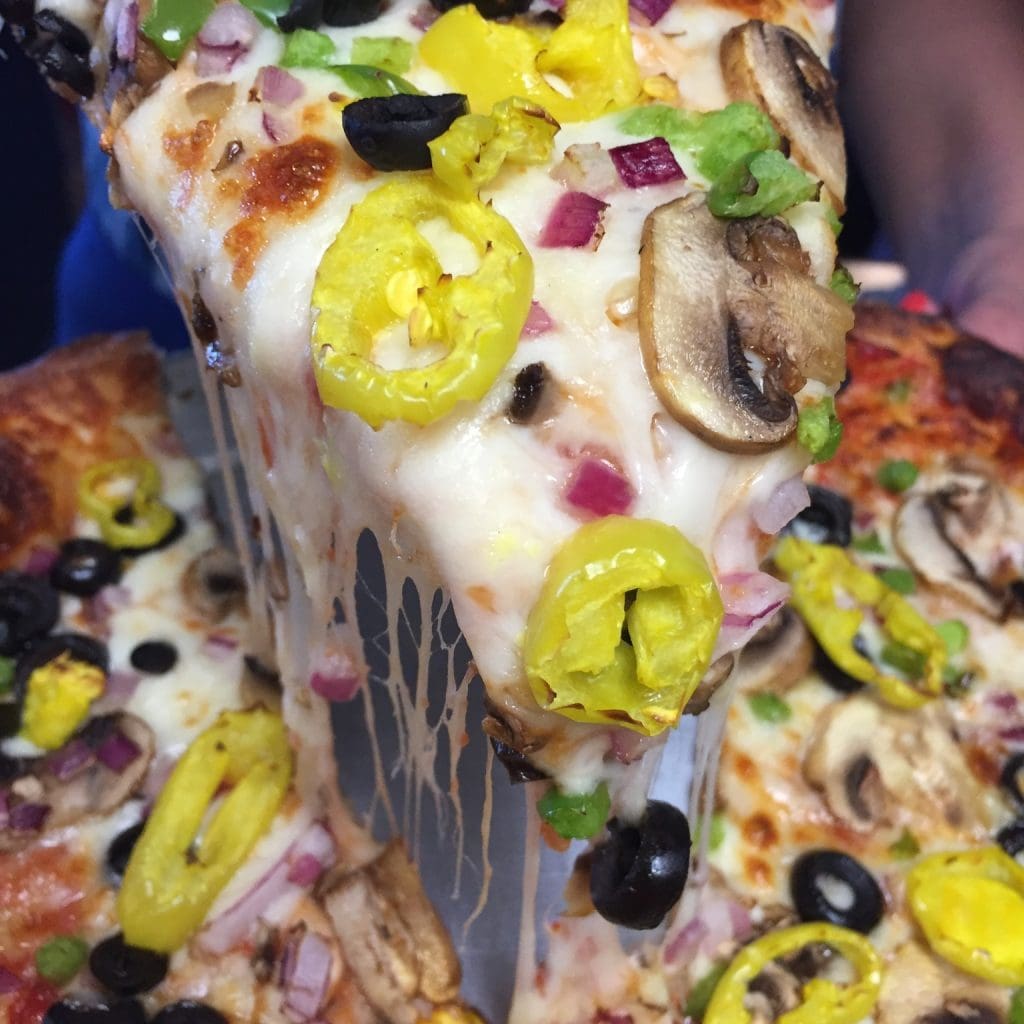 A slice of pizza with vegetables
Description automatically generated